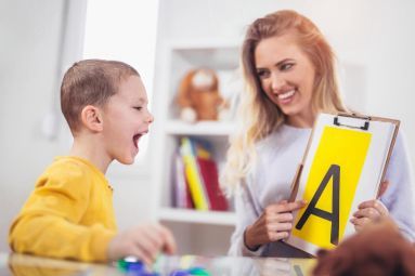 Un’assistente all’autonomia e alla comunicazione insieme a un bimbo con disabilità