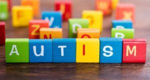 Alcune lettere scritte su tasselli di legno colorato compongono la scritta “Autism”.