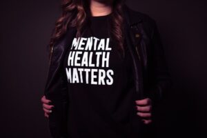 Una ragazza, che indossa una maglietta nera, mostra la scritta bianca stampata su di essa: “Mental Health Matters”, ovvero “La salute mentale conta” (foto di Matthew Ball su Unsplash).