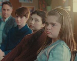 Un’adolescente con sindrome di Down persone con un’espressione un po’ accigliata assieme ad altre.