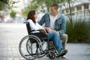 Un volontario insieme a una giovane donna in sedia a rotelle.
