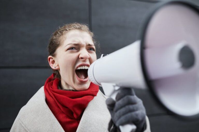 Una giovane donna amplifica il suo urlo attraverso un megafono (foto: Pexels).