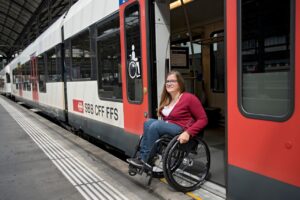 Una giovane donna in sedia a rotelle esce in autonomia da un treno accessibile.