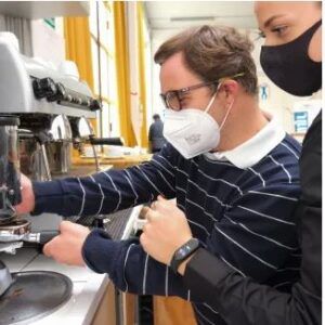 Un giovane con disabilità del progetto “I FormidAbili” alle prese con una macchina da caffè, sotto la supervisione di una collaboratrice, all’interno di un Makers Caffè.