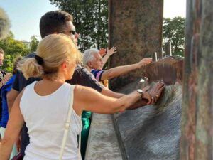 Alcune persone cieche, accompagnate dai rispettivi accompagnatori e accompagnatrici, mentre toccano una delle opere dello scultore belga Jean-Michel Folon ospitata nel Giardino delle Rose di Firenze (fonte: «intoscana»).