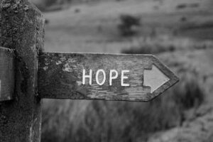 Immagine in bianco e nero di un cartello direzionale con la scritta “hope” (speranza).