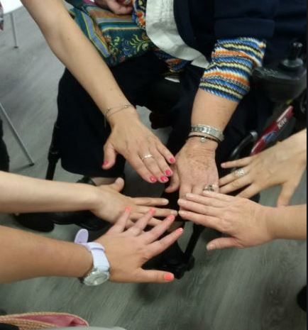 Le mani di alcune donne convergono in un centro immaginario in segno di sorellanza.