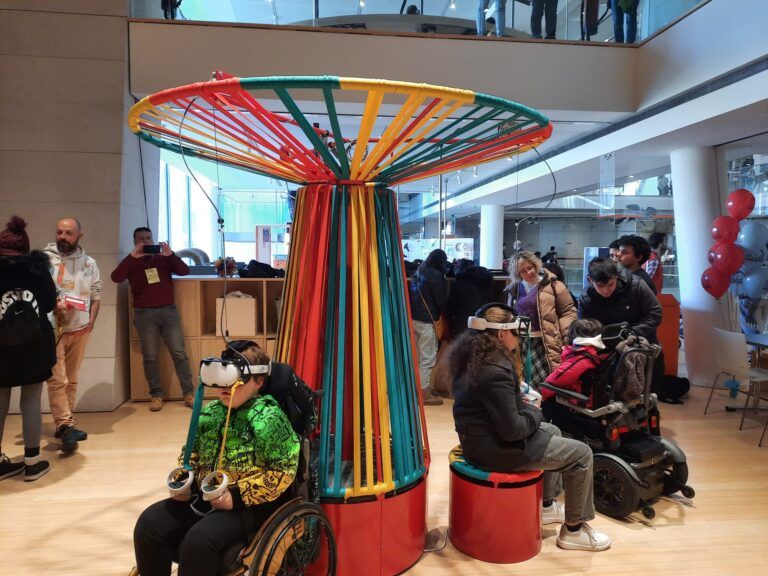 Un bambino con disabilità ed una ragazza, circondati da altre persone, vivono un’esperienza di realtà virtuale al “Mirko Park”, un lunapark virtuale accessibile intitolato a Mirko Toller, inaugurato lo scorso 3 dicembre presso il Museo delle Scienze di Trento.