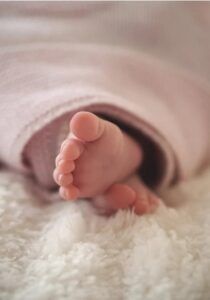 I piedini di un neonato sbucano da una copertina (fonte Pexels).