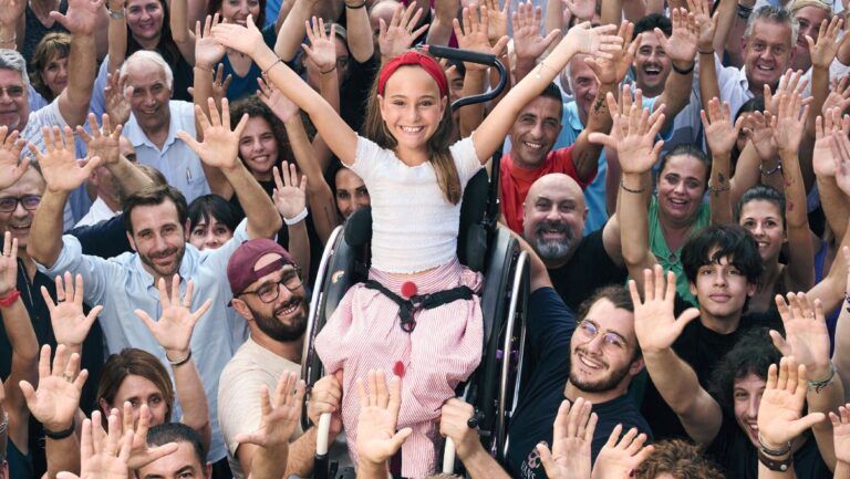 L’immagine scelta per promuovere la Maratona Telethon 2023 è quella che raffigura una giovanissima e sorridente ragazza in sedia a rotelle che alza le braccia in alto in segno di libertà, ed è sorretta dalle tante mani di una moltitudine di persone, anch’esse con le braccia alzate.