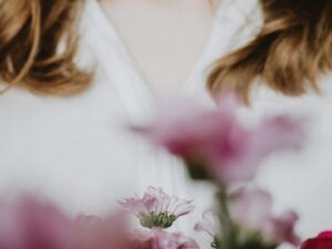 Immagine sfuocata di una figura femminile davanti a dei fiori rosa (foto di Anastasia Zhenina).
